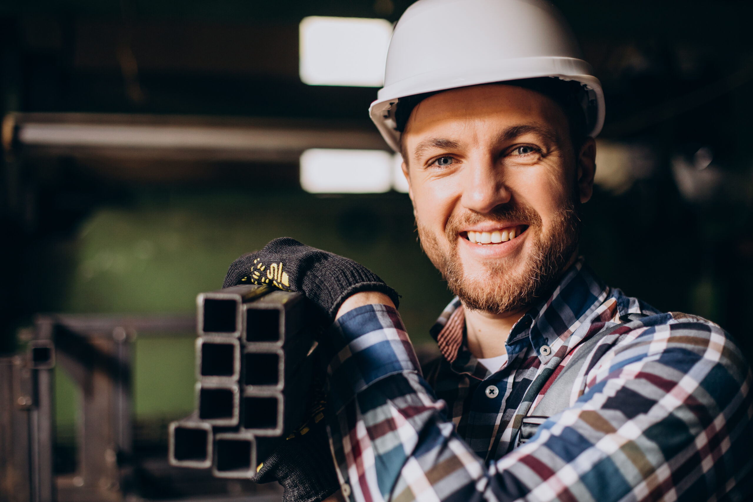 Workman wearing hard hat working with metal constructions at factory